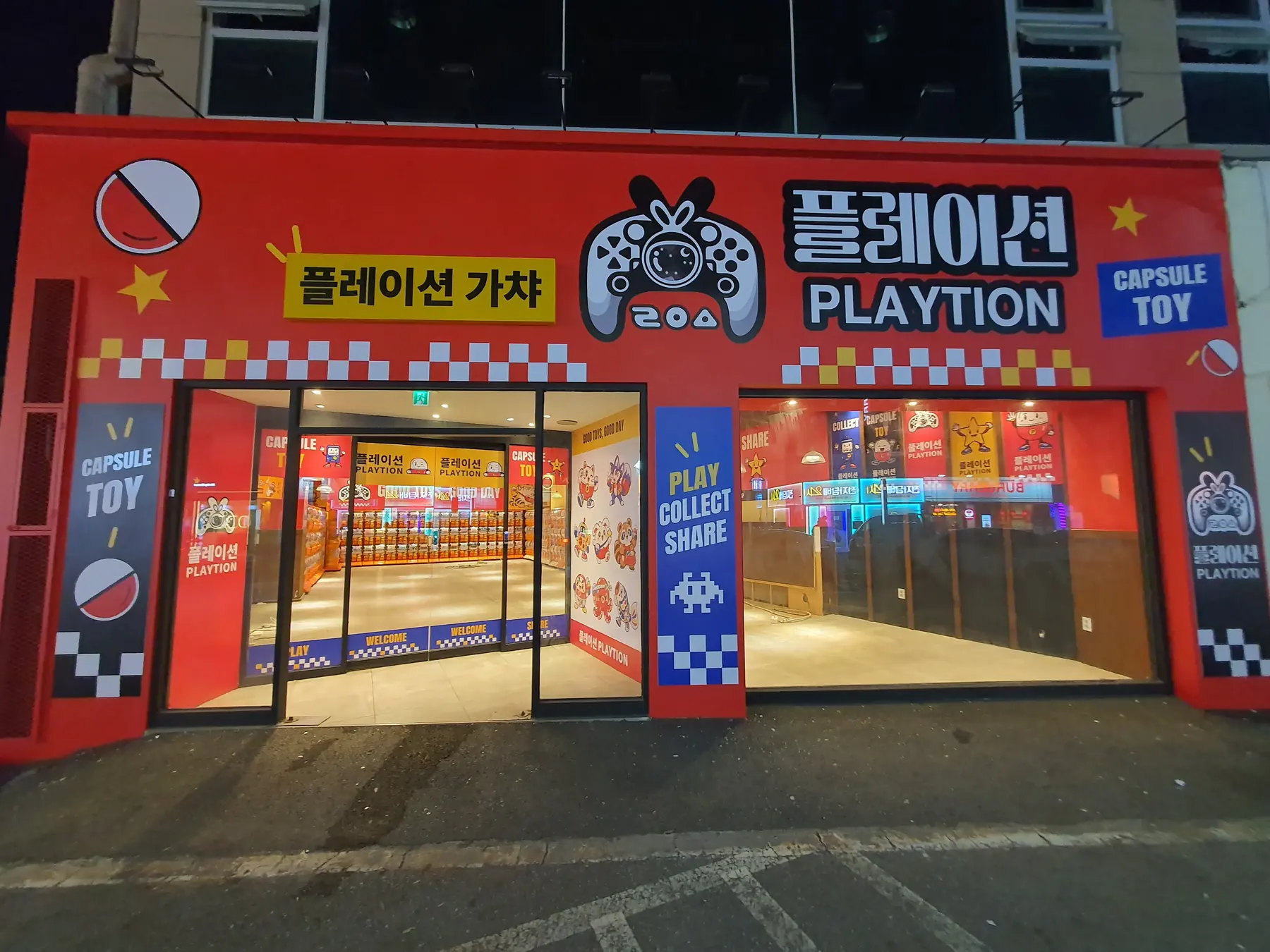 빨간 외벽에 플레이션 간판이 걸린 가챠샵 전경. 유리문 너머로 주황색 캡슐토이 기기가 줄지어 보인다